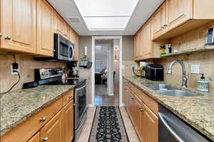 Kitchen with light stone countertops, appliances with stainless steel finishes, sink, and tasteful backsplash