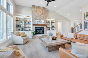 Living room with a wealth of natural light, vaulted ceiling, ceiling fan, and a fireplace