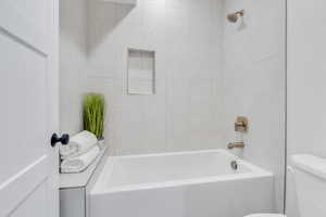 Bathroom featuring tiled shower / bath and toilet