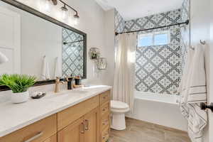 Full bathroom with vanity, toilet, shower / bath combo with shower curtain, and tile patterned floors