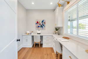 Home office / craft room with built in desk and light hardwood / wood-style floors