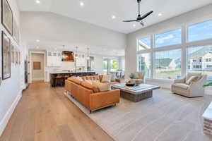 Living room featuring light hardwood / wood-style flooring, a wealth of natural light, ceiling fan, and high vaulted ceiling