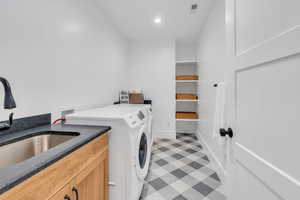 Laundry room with cabinets, separate washer and dryer, and sink