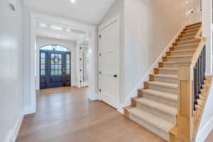 Entrance foyer featuring light hardwood / wood-style flooring and lofted ceiling