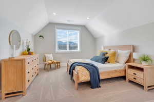 Bedroom with light colored carpet and vaulted ceiling