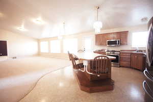 Kitchen with an inviting chandelier, stainless steel appliances, hanging light fixtures, and a healthy amount of sunlight