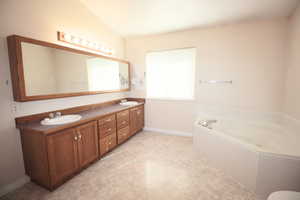 Master Bathroom featuring lofted ceiling, huge jetted bath, and vanity