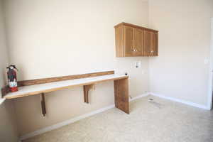 Clothes washing area with washer hookup, light carpet, cabinets, and electric dryer hookup