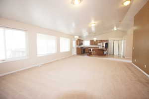 Unfurnished living room with lofted ceiling and light colored carpet