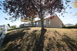 View of side of home with a deck and a lawn