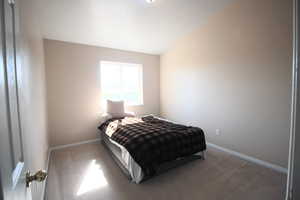 Bedroom 3 with a textured ceiling, vaulted ceiling, and carpet flooring