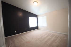 Master Bedroom featuring light colored carpet, a textured ceiling, and vaulted ceiling