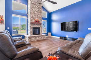 Living room featuring high vaulted ceiling, a stone fireplace, a mountain view