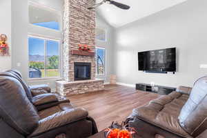 Living room featuring a mountain view, ceiling fan, high vaulted ceiling, a fireplace, and hardwood / wood-style floors