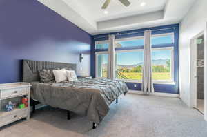 Primary bedroom with ceiling fan, a mountain view, natural light and a raised ceiling