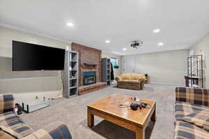 Living room with light carpet, ornamental molding, and a fireplace