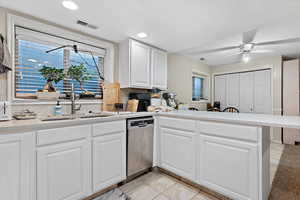 Kitchen featuring white cabinets, backsplash, kitchen peninsula, dishwasher, and ceiling fan