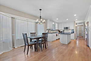 Dining space with sink, light hardwood / wood-style flooring, and a chandelier