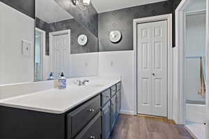 Bathroom featuring hardwood / wood-style floors, vanity, and combined bath / shower with glass door