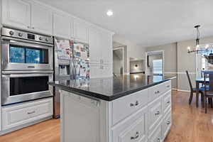 Kitchen featuring appliances with stainless steel finishes, plenty of natural light, a chandelier, and white cabinetry