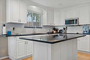 Kitchen with white cabinets, sink, and a kitchen island