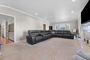 Living room featuring light carpet, crown molding, and vaulted ceiling