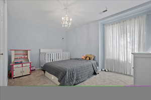 Bedroom with light carpet and an inviting chandelier