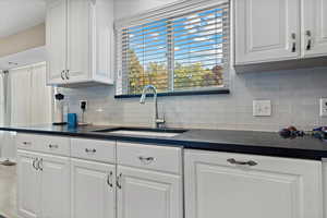 Kitchen featuring backsplash, white cabinetry, and sink