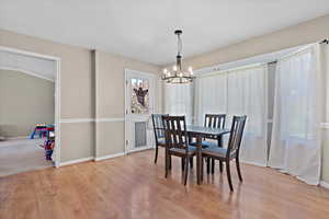 Dining room with light wood-type flooring and a chandelier