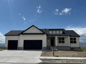 View of front of home with a garage, a standing seam roof, metal roof, a porch, and driveway