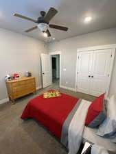 Carpeted bedroom featuring ceiling fan and a closet