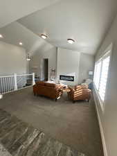 Carpeted living room with a fireplace and vaulted ceiling