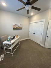 Interior space featuring dark colored carpet and ceiling fan