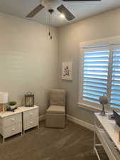 Living area featuring ceiling fan and dark carpet