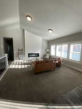 Living room featuring dark carpet, lofted ceiling, and a fireplace