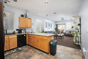 Kitchen featuring kitchen peninsula, sink, ceiling fan, and black dishwasher