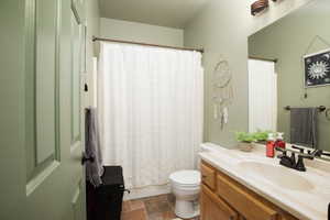 Bathroom with curtained shower, vanity, and toilet