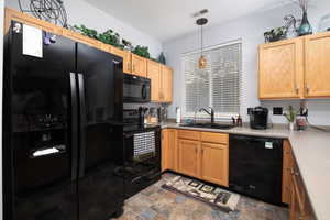 Kitchen with pendant lighting, black appliances, and sink