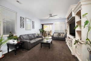 Carpeted living room with ceiling fan