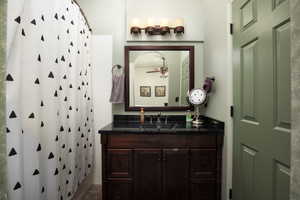 Bathroom featuring ceiling fan, vanity, walk in shower, tile walls, and tile patterned flooring