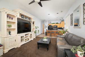 Living room with dark colored carpet and ceiling fan