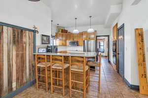 Kitchen featuring appliances with stainless steel finishes, tasteful backsplash, a breakfast bar, kitchen peninsula, and decorative light fixtures