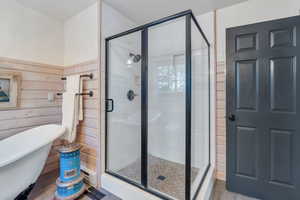 Bathroom featuring plus walk in shower, wood walls, and hardwood / wood-style flooring