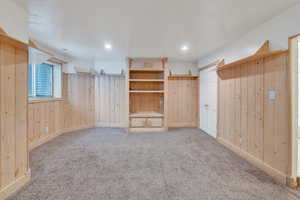 Unfurnished bedroom with wooden walls, a closet, and light colored carpet