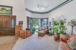 Sitting room with track lighting, light tile patterned floors, a textured ceiling, and a high ceiling