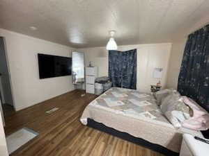 Bedroom with a textured ceiling and dark hardwood / wood-style floors