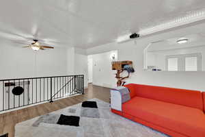 Living room featuring wood-type flooring, a textured ceiling, and ceiling fan