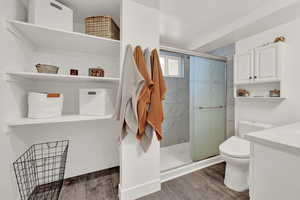 Bathroom with wood-type flooring, vanity, toilet, and a shower with shower door