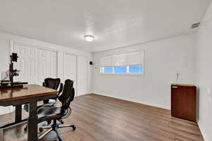 Office featuring light wood-type flooring and a textured ceiling