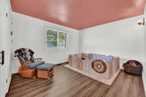 Sitting room with a textured ceiling and hardwood / wood-style floors